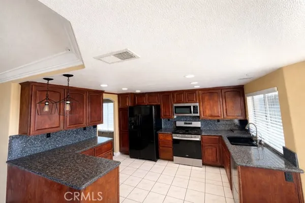 a kitchen with granite countertop stainless steel appliances a stove refrigerator and cabinets