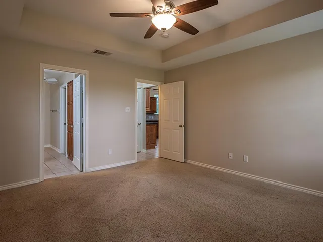 a view of an empty room and chandelier fan