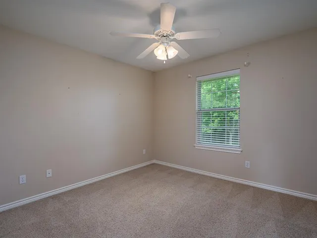 an empty room with a chandelier fan and windows
