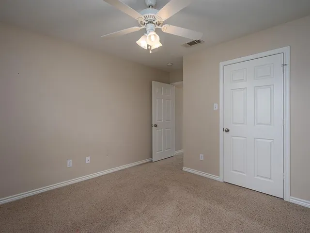 an empty room with closet and a ceiling fan