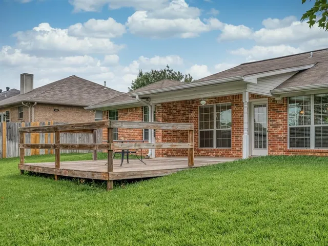 a view of a house with a backyard and wooden fence