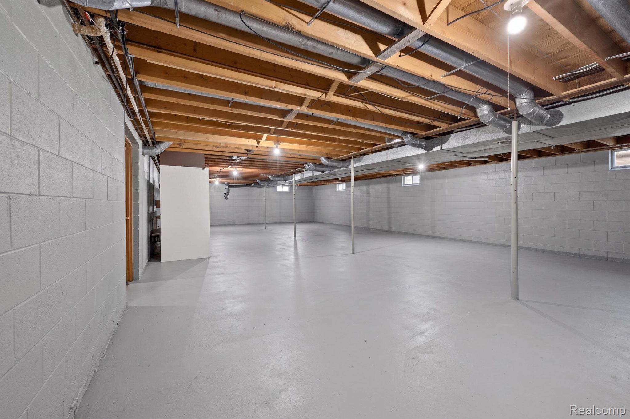 5330 Sheridan Road Saginaw, MI 48601 - Photo 39 of 50 Expansive unfinished basement featuring painted concrete block walls, a painted concrete floor, exposed wood ceiling joists, and overhead lighting