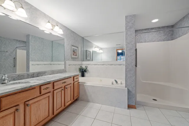 a spacious bathroom with a granite countertop sink a toilet mirror and bathtub