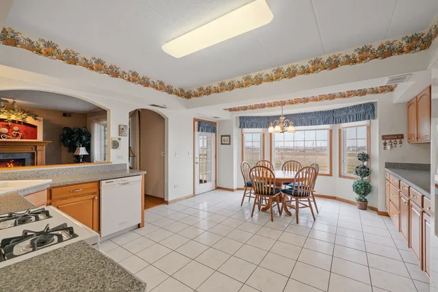 a dining hall with stainless steel appliances granite countertop a stove and white cabinets next to a window
