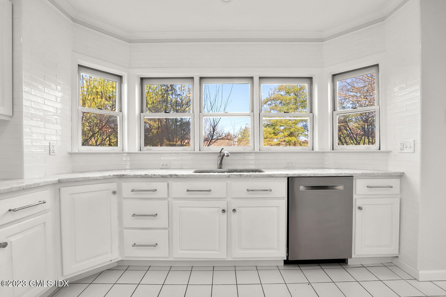 a kitchen with white cabinets and window