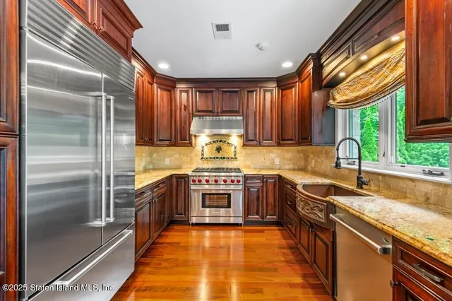 a kitchen with stainless steel appliances wooden cabinets and a stove top oven