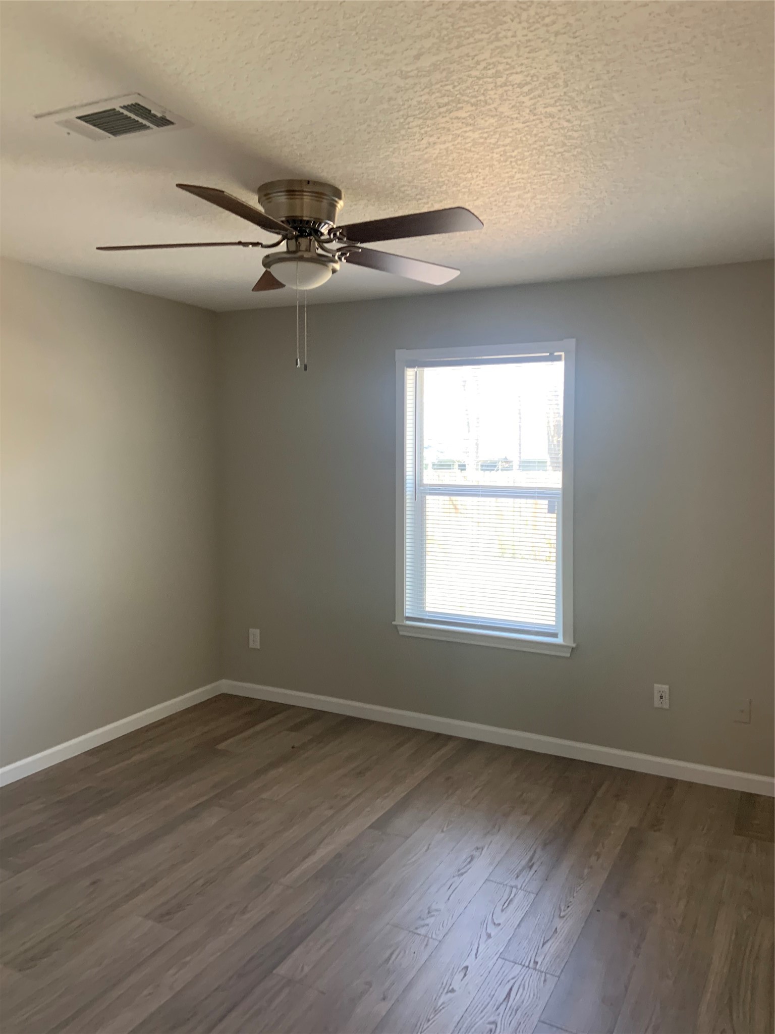 10978 Youpon Street Cleveland, TX 77328 - Photo 9 of 24 an empty room with wooden floor windows and fan