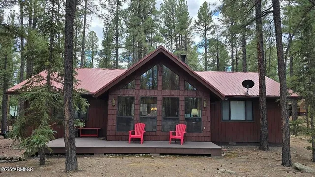 a view of wooden house with large windows and a tree