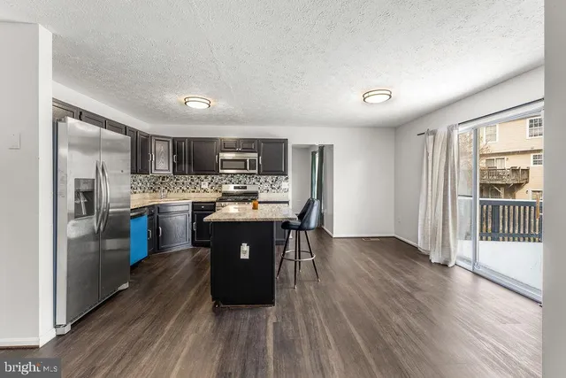 a kitchen with stainless steel appliances a refrigerator a sink dishwasher a stove and a oven with wooden floor