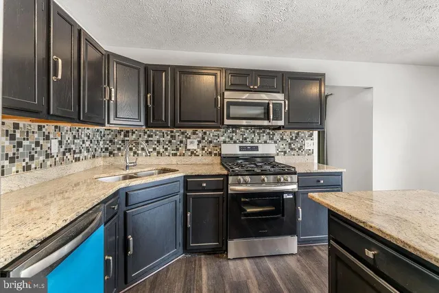 a kitchen with stainless steel appliances granite countertop wooden cabinets stove top oven and sink