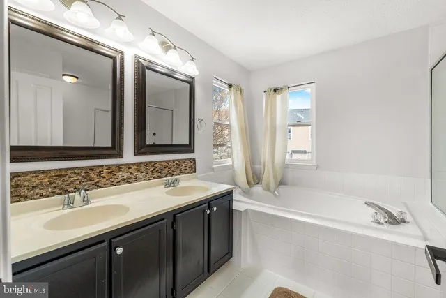 a bathroom with a tub sink and mirror