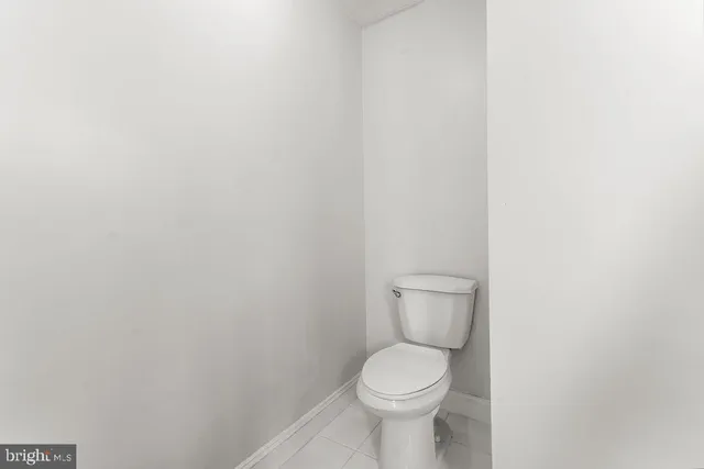a white toilet sitting next to a white wall