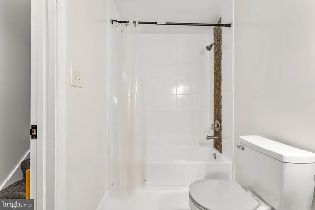 a white toilet sitting next to a bath tub