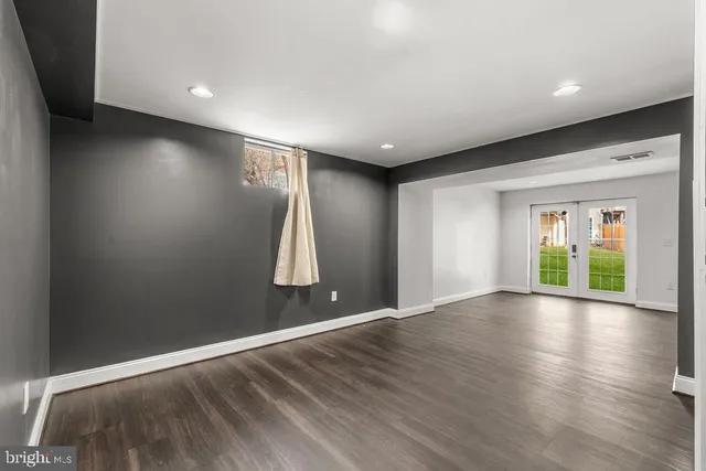 an empty room with wooden floor and windows