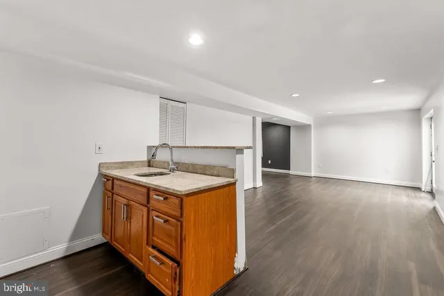 an empty room with a sink and wooden floor