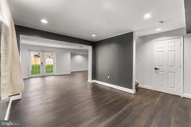 a view of an empty room with wooden floor and windows