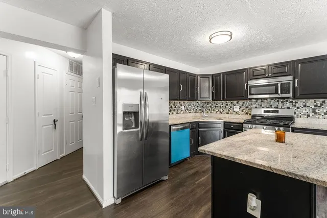 a kitchen with kitchen island granite countertop stainless steel appliances and wooden cabinets