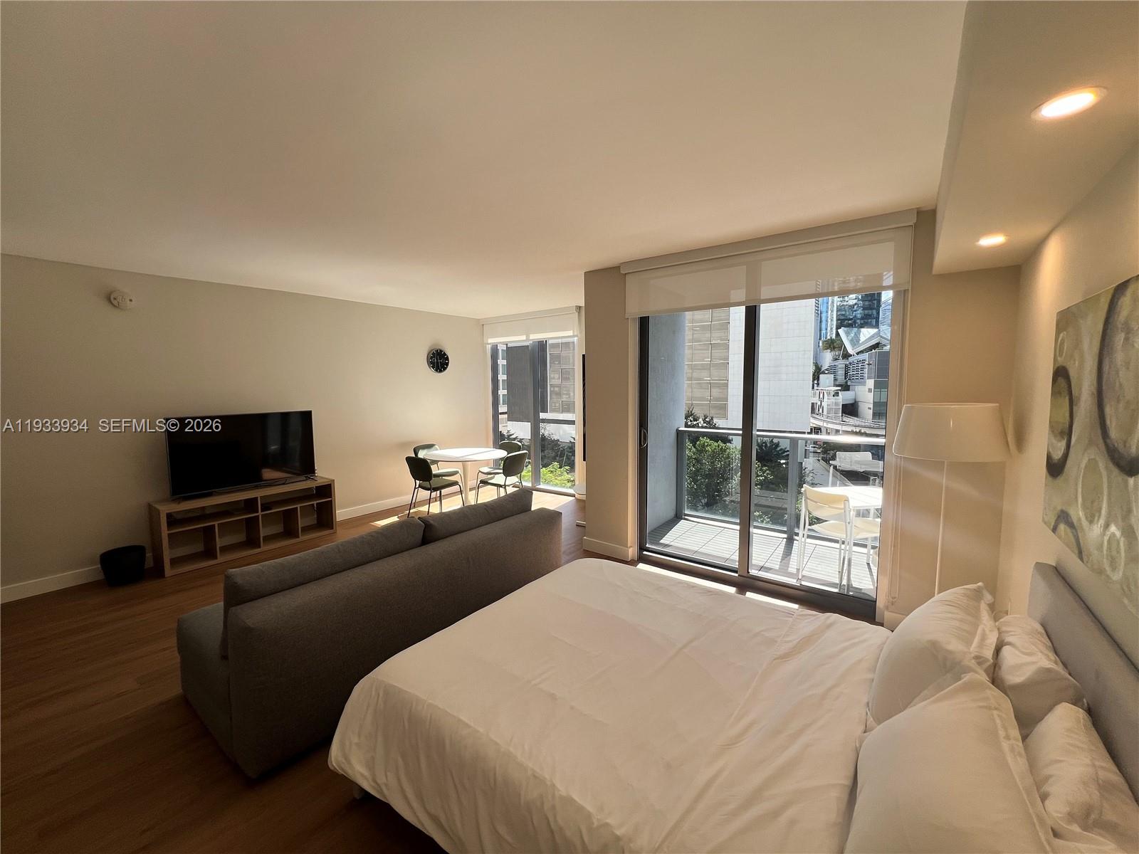 31 Southeast 6th Street, Unit 703 Miami, FL 33131 - Photo 11 of 16 a bedroom with a bed and a flat tv screen on the dresser