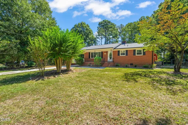 a view of a house with backyard and trees