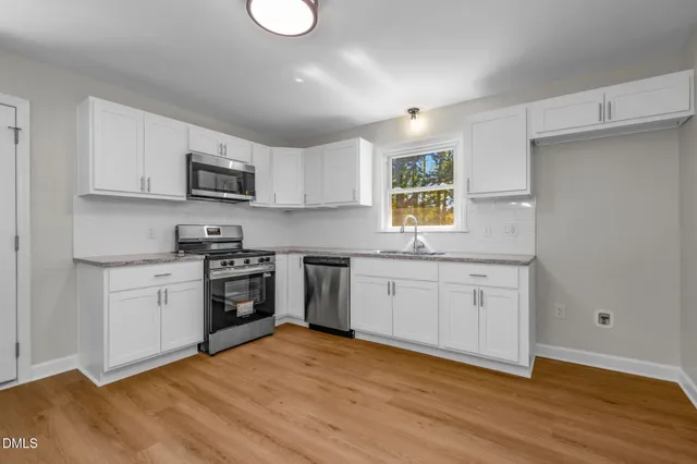 a kitchen with granite countertop a stove a sink and a wooden floors