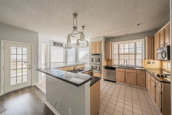 a kitchen with stainless steel appliances granite countertop a stove a sink dishwasher a refrigerator and white cabinets with wooden floor