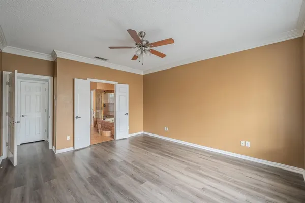 a view of an empty room with wooden floor and a ceiling fan