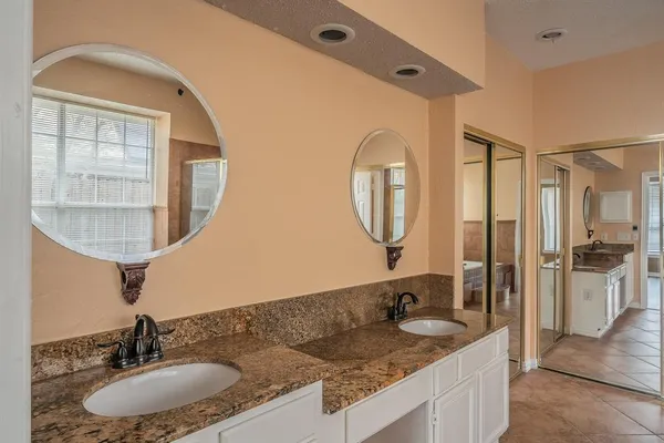 a bathroom with a granite countertop double vanity sink and a mirror