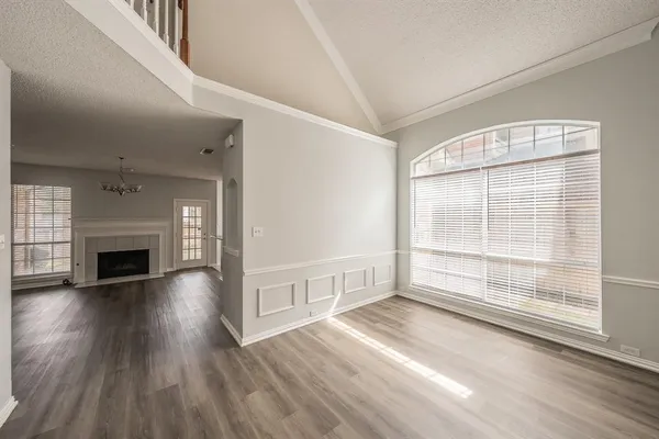 an empty room with wooden floor fireplace and windows