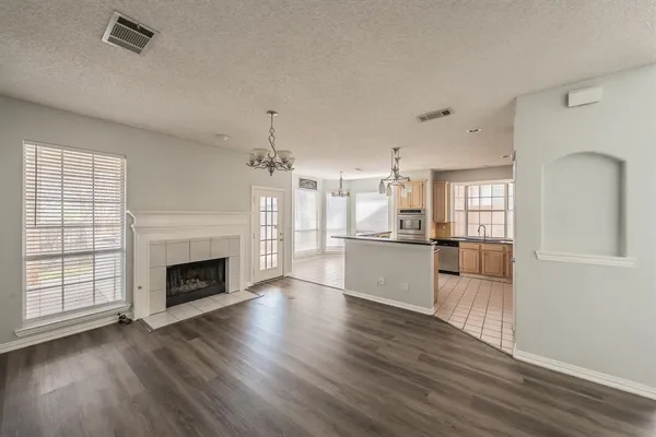 an empty room with wooden floor fireplace and windows