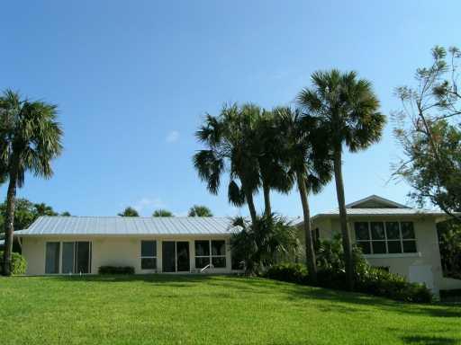 27 North River Road Stuart, FL 34996 - Photo 6 of 8 a front view of a house with a garden and trees