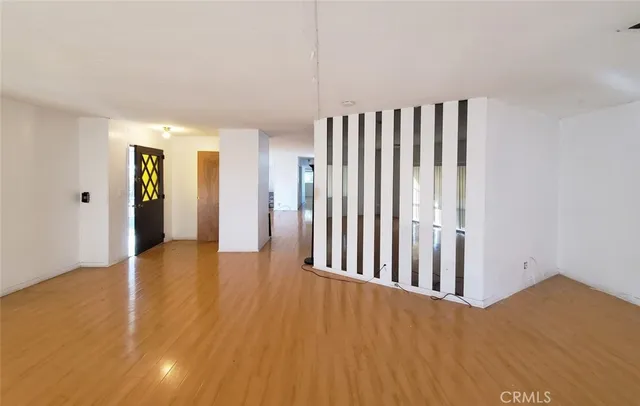 a view of an empty room with wooden floor and a window