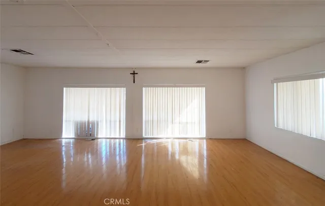 a view of empty room with wooden floor and fan