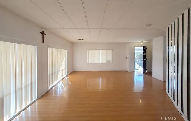 a view of an empty room with kitchen and a window