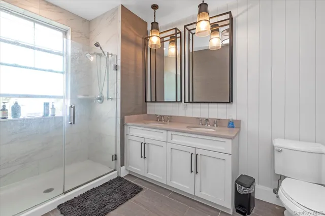 a bathroom with a shower a sink a toilet and mirror