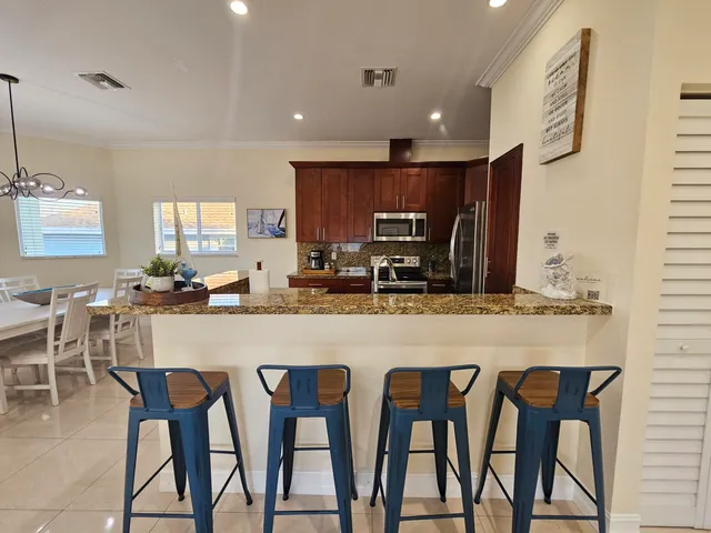 a kitchen with kitchen island granite countertop wooden cabinets and chairs