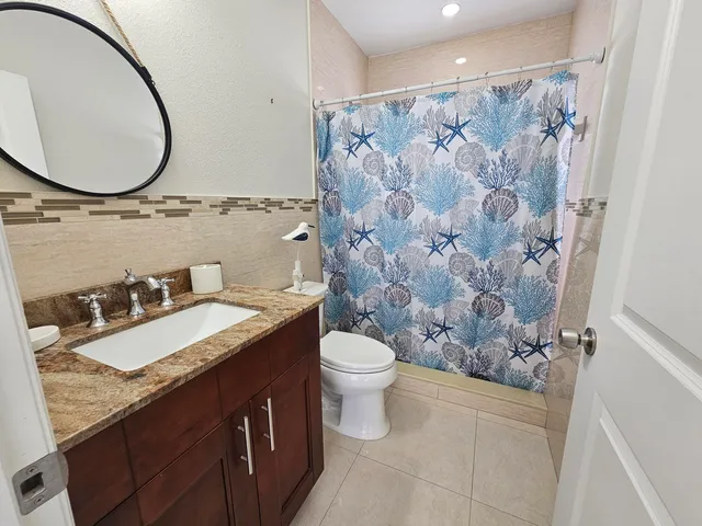 a bathroom with a granite countertop sink toilet and a mirror