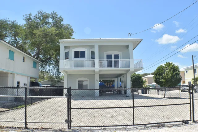 a view of a white house with large windows and palm tree