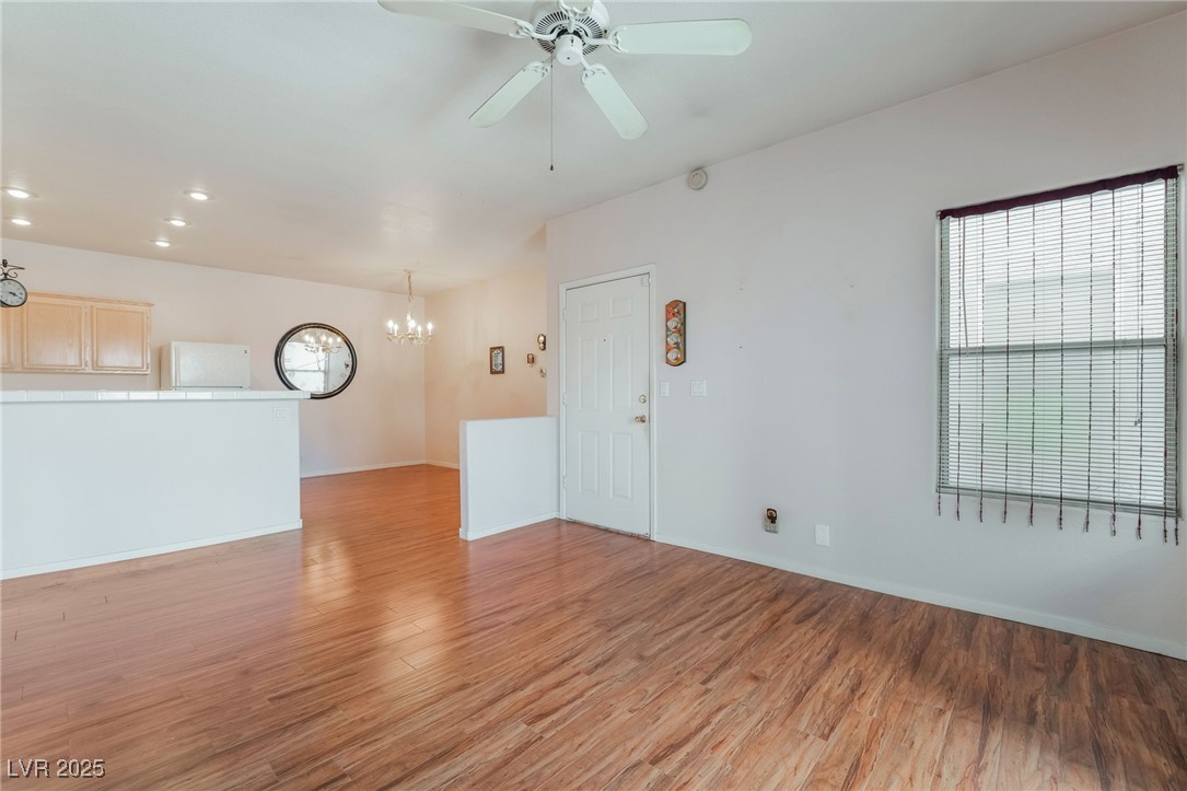 2201 Ramsgate Drive, Unit 823 Henderson, NV 89074 - Photo 5 of 31 Empty room featuring baseboards, plenty of natural light, ceiling fan with notable chandelier, and light wood finished floors