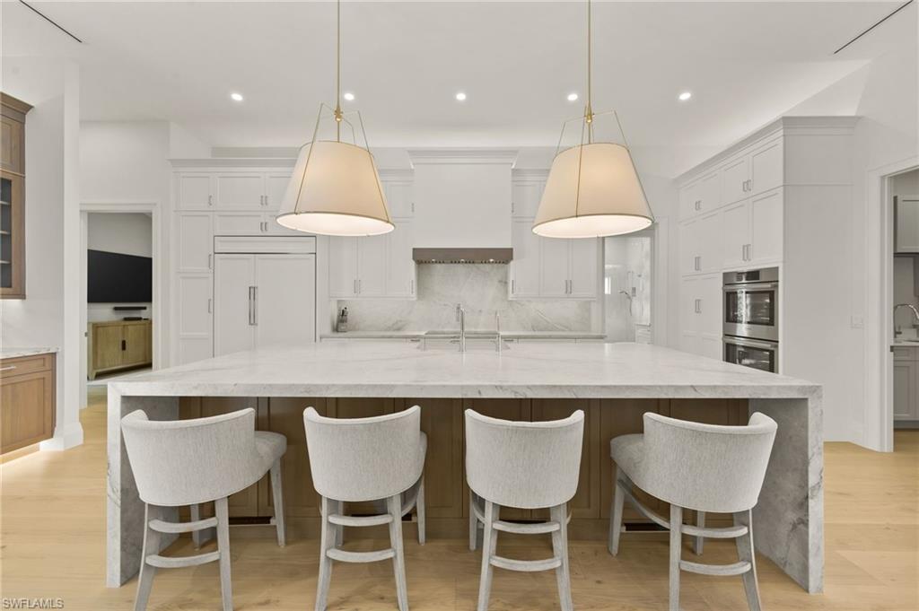 6689 Mill Run Road Naples, FL 34109 - Photo 13 of 37 a kitchen with granite countertop white cabinets and chairs