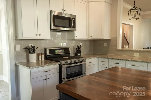 a kitchen with stainless steel appliances granite countertop a stove a sink and a microwave