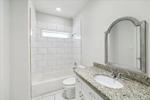 a bathroom with a granite countertop sink a toilet and bathtub