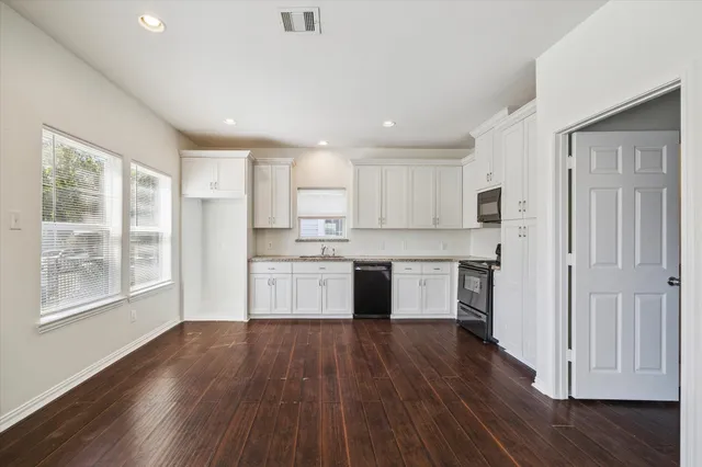 a kitchen with wooden floors and white cabinets