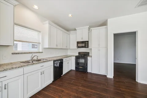a kitchen with granite countertop white cabinets and wooden floor