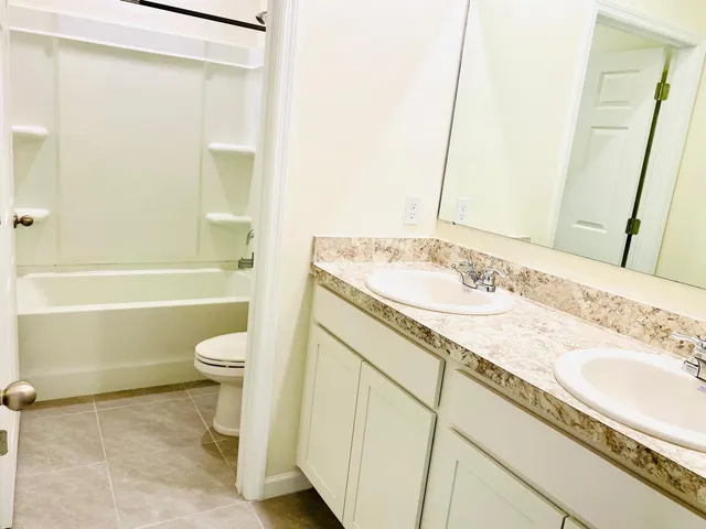a bathroom with a granite countertop toilet and a sink