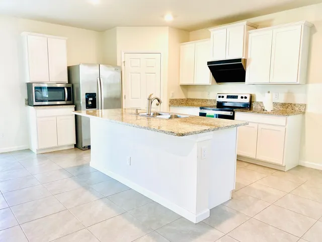 a kitchen with stainless steel appliances granite countertop a stove a sink a microwave a refrigerator a cabinets and a refrigerator