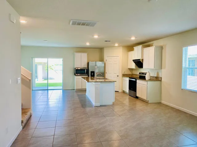 a kitchen with stainless steel appliances granite countertop a stove top oven a sink a dining table and chairs