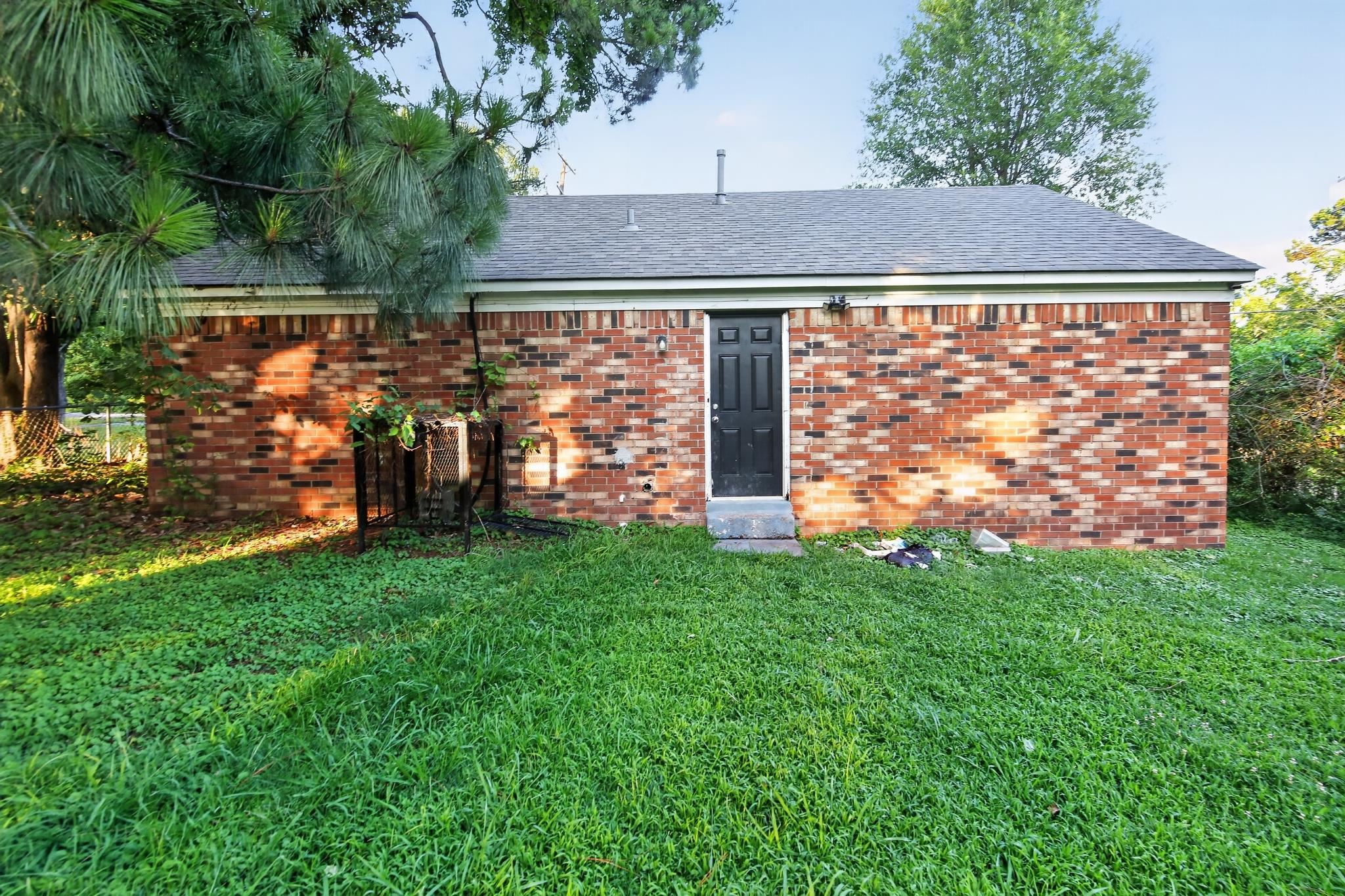 3953 McCain Road Memphis, TN 38109 - Photo 3 of 15 Brick exterior featuring a black entry door with transom window, concrete steps, and a dark shingle roof
