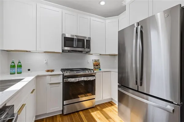 a kitchen with stainless steel appliances white cabinets white stove a microwave and a refrigerator