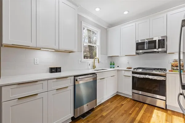 a kitchen with stainless steel appliances granite countertop white cabinets a sink a stove and a microwave