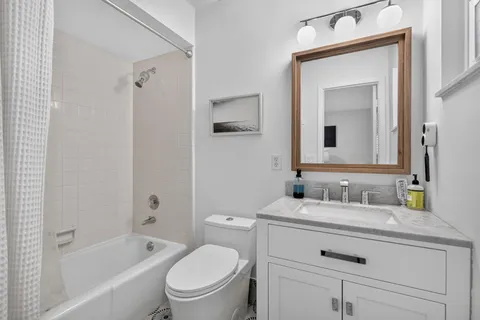 a bathroom with a sink vanity mirror toilet and bathtub